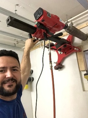 Kernbohrgerät an der Decke im Einsatz, Inhaber im Vordergrund
